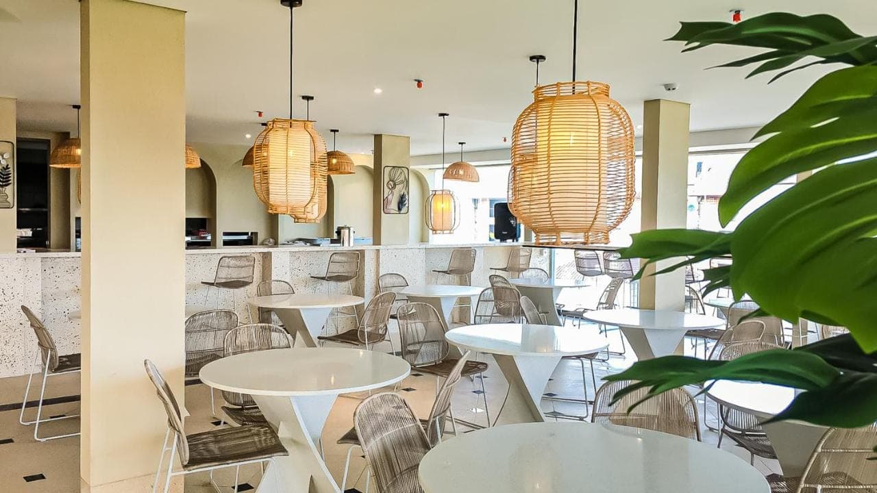 a restaurant with white tables and chairs and lights at Aster Apartment Bali in Canggu