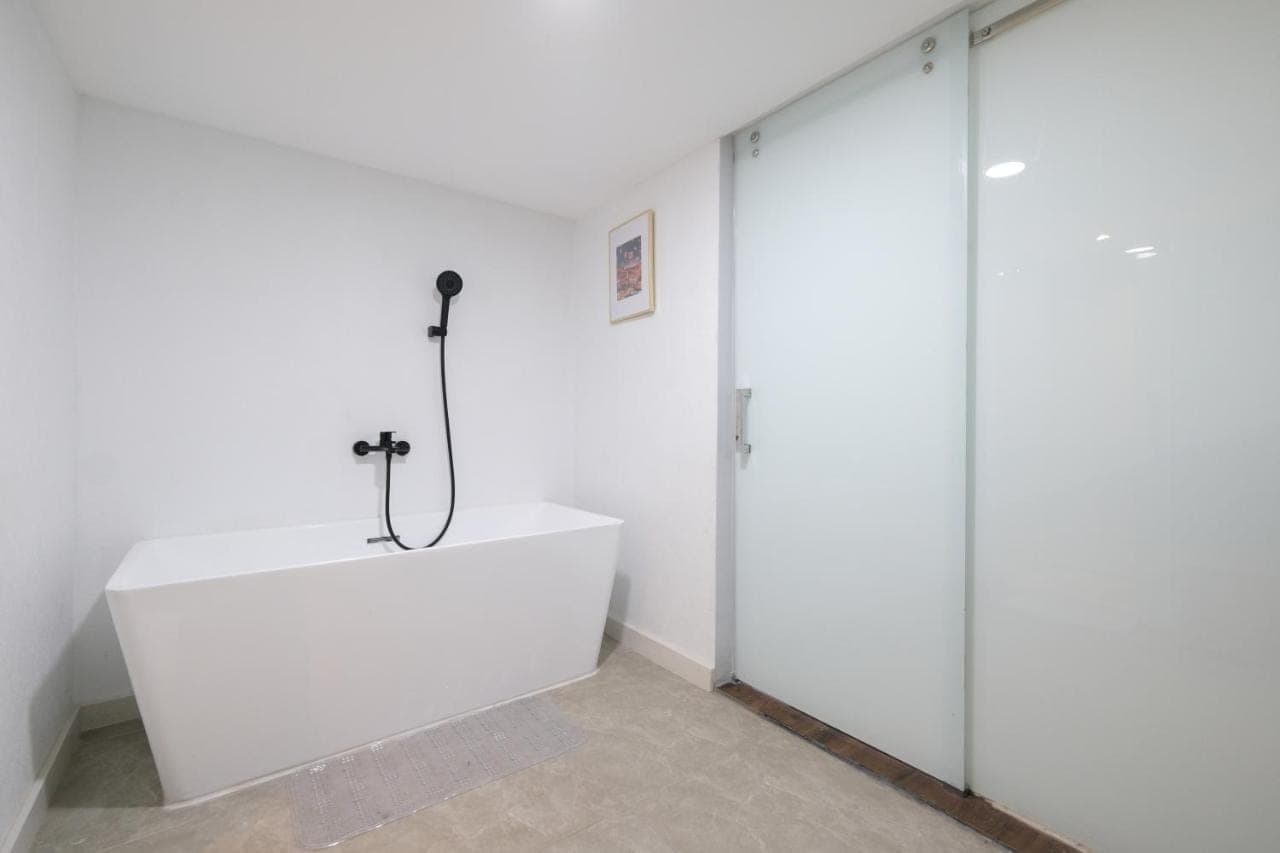 a white bath tub in a room with glass walls at Aster Apartment Bali in Canggu