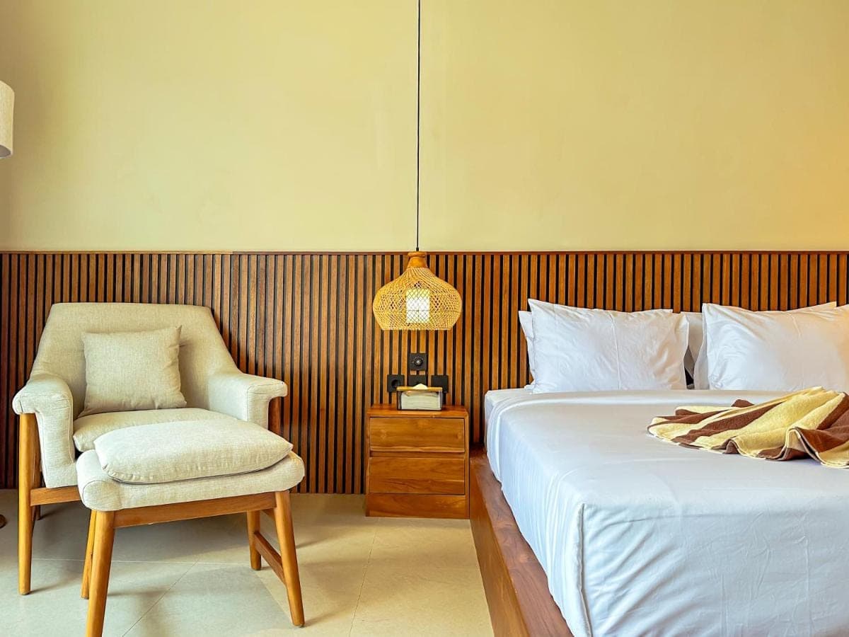 a bedroom with a bed and a chair and a lamp at Poh Canggu Guesthouse in Canggu