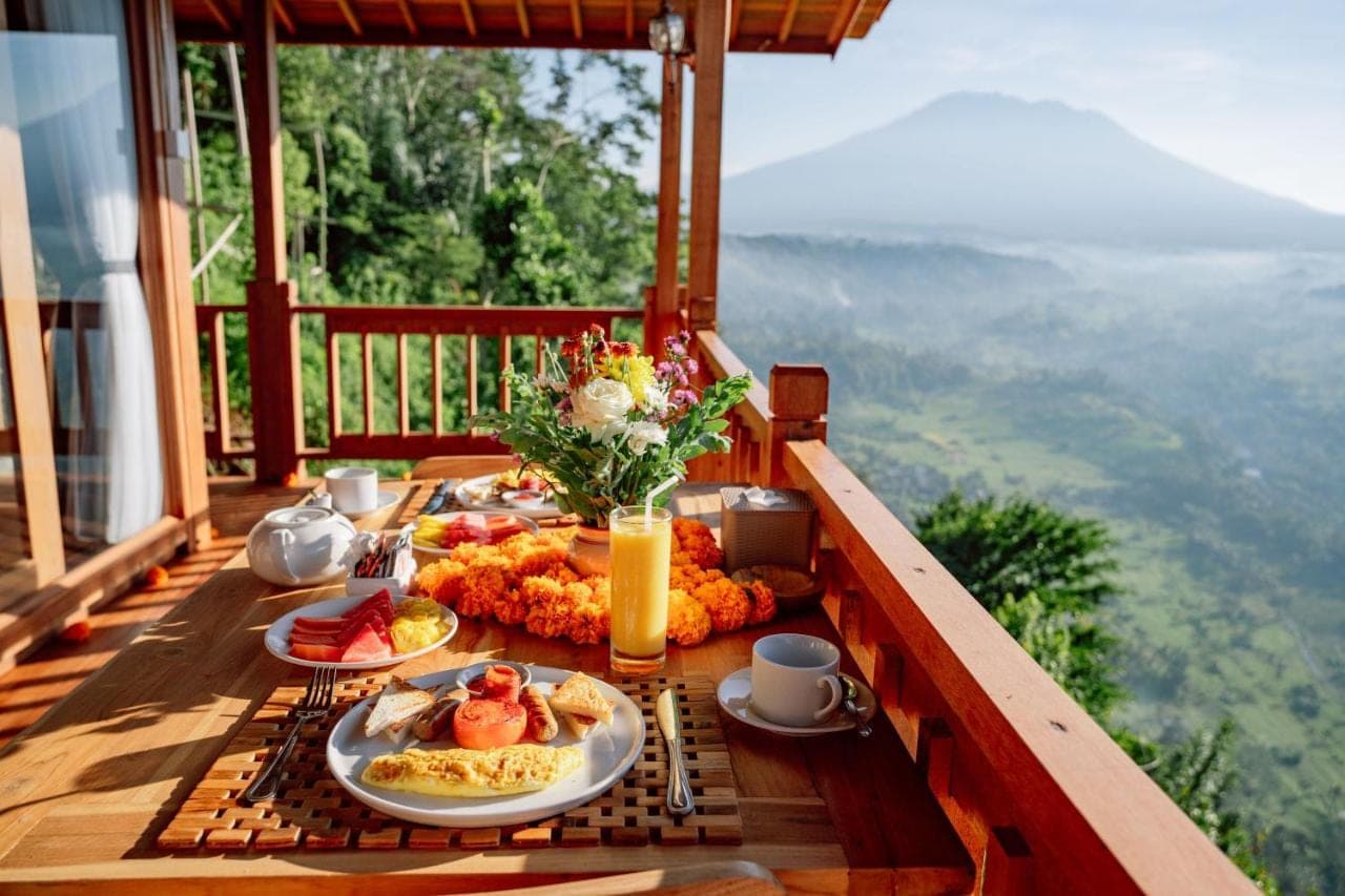 a breakfast table on a balcony with food on it at Pitak Hill Villa Sidemen in Sidemen