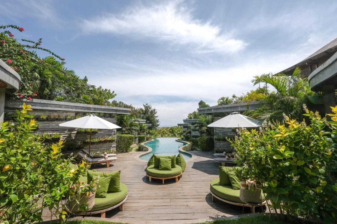 a patio with green chairs and a swimming pool at The Elementum in Uluwatu