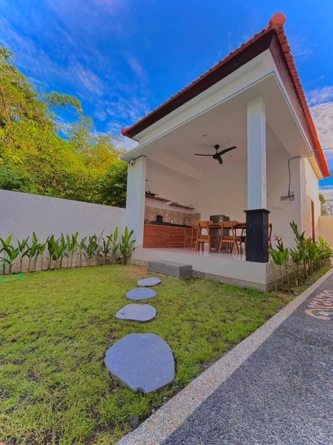 a house with a lawn with stepping stones in front of it at Amitha Lodge Uluwatu in Uluwatu