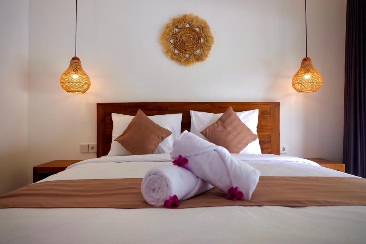 a bedroom with a bed with white sheets and pillows at Amitha Lodge Uluwatu in Uluwatu