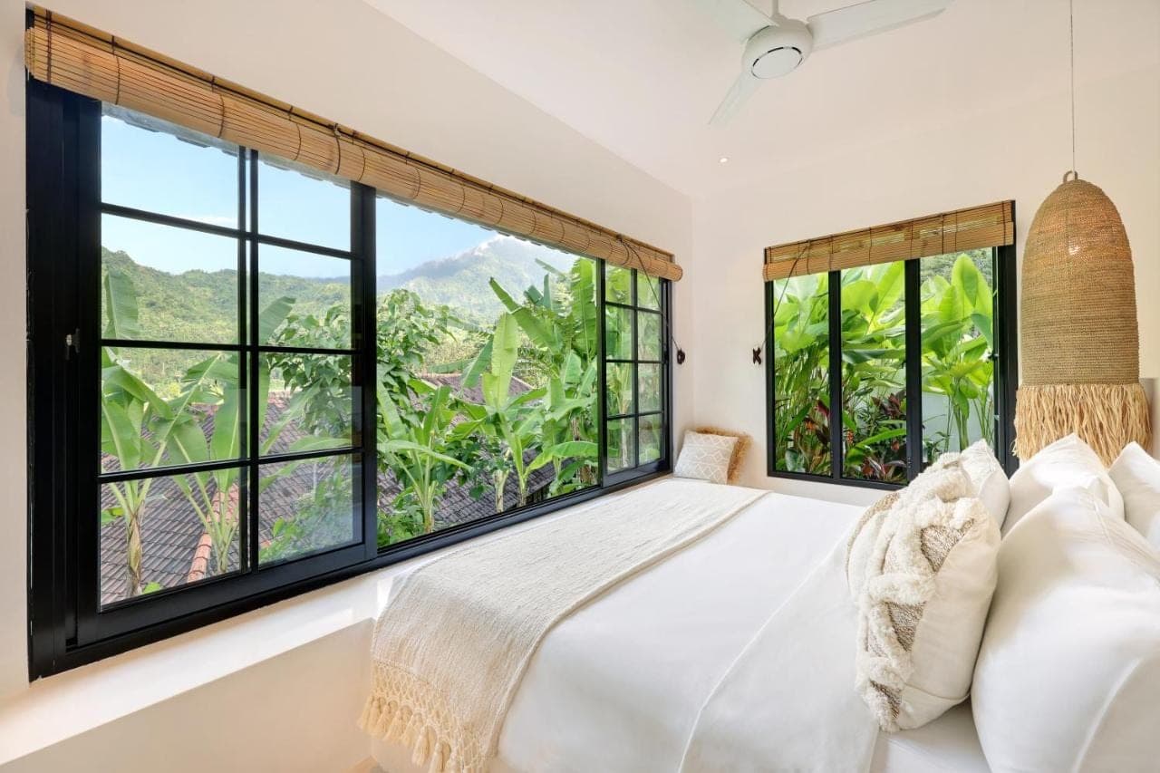 a bedroom with a bed and large windows at Tropical Habitat Bali in Amed