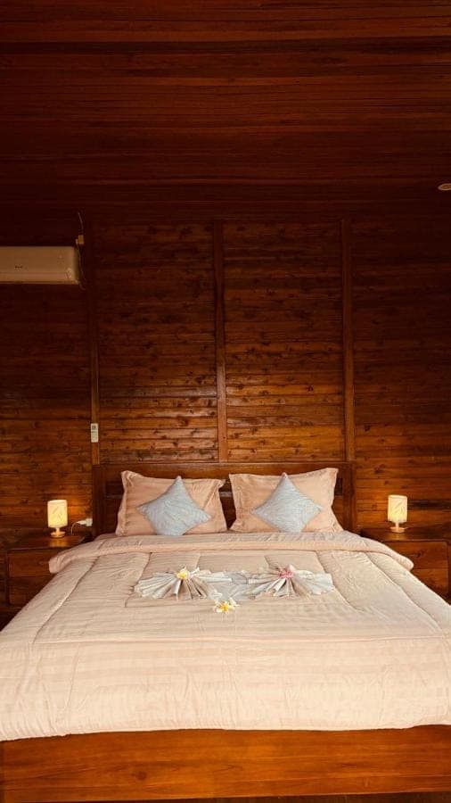 a large bed with white sheets and flowers on it at Mantra Guesthouse Sidemen in Sidemen