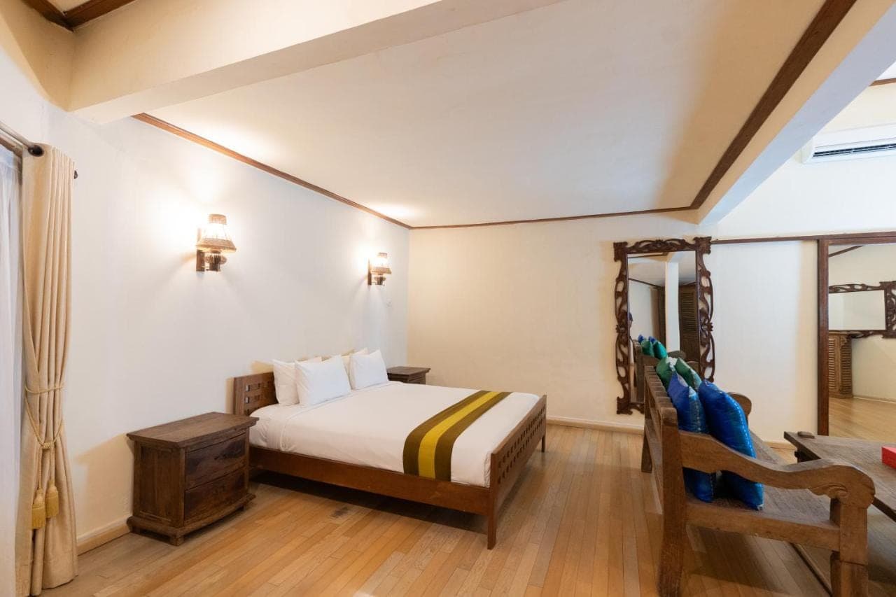 a bedroom with a bed and a chair in a room at The Flora Kuta Bali in Kuta