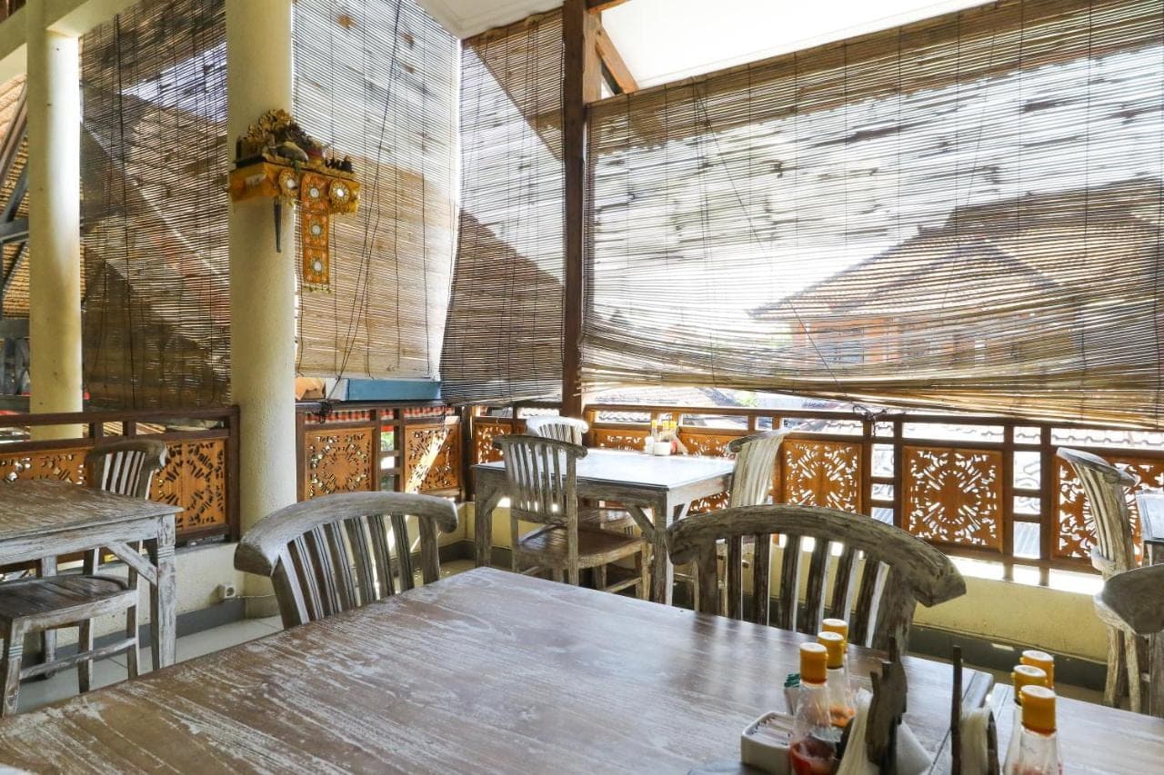 a restaurant with tables and chairs and a large window at The Flora Kuta Bali in Kuta