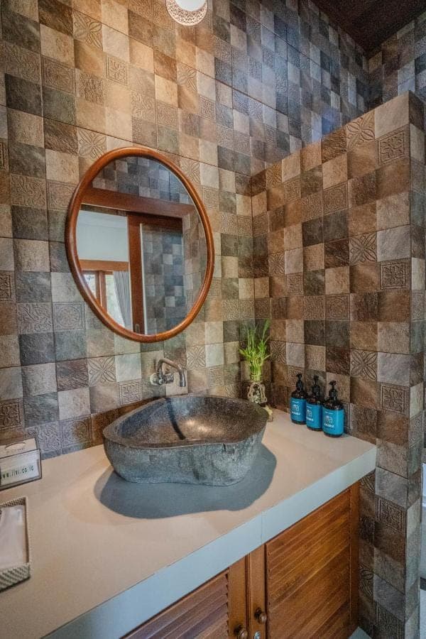 a bathroom with a stone sink and a mirror at Zaara Guesthouse Uluwatu in Uluwatu