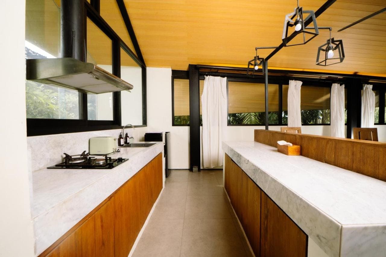 a kitchen with white counter tops and wooden cabinets at Mono Villa - Nusa Dua in Nusa Dua
