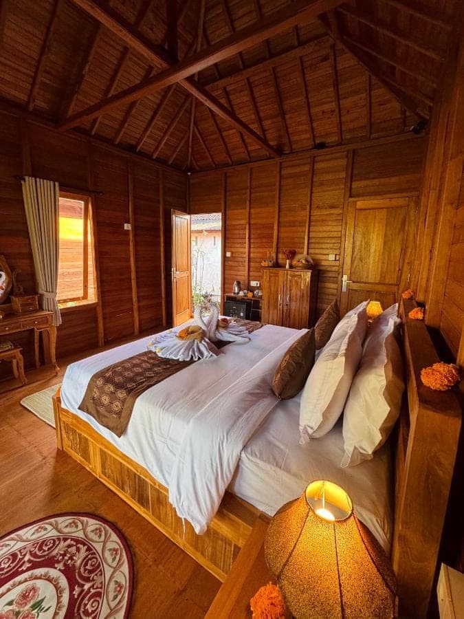 a bedroom with a large bed in a wooden room at Deva Graha Sidemen in Sidemen