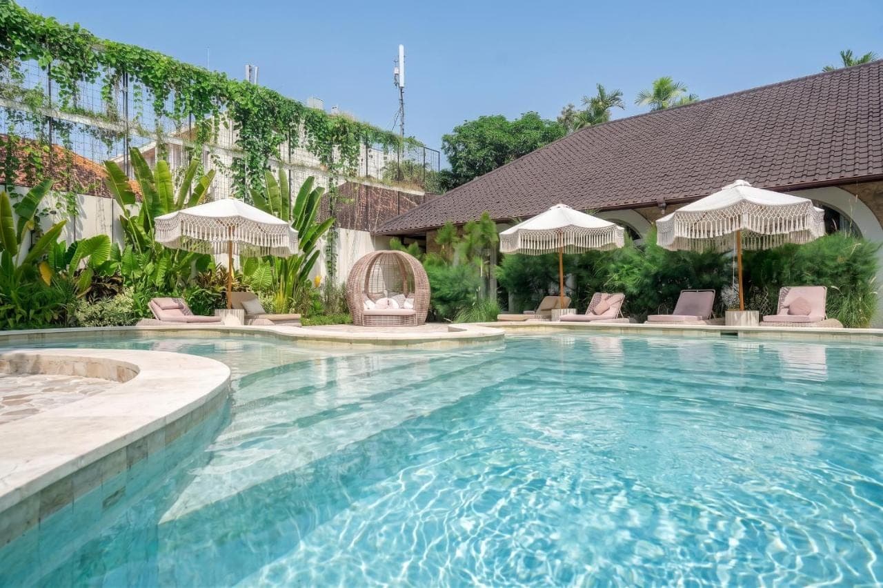 a swimming pool with chairs and umbrellas at Maison Boheme Modern Apartment &amp; Villa with Pool in Sanur in Sanur