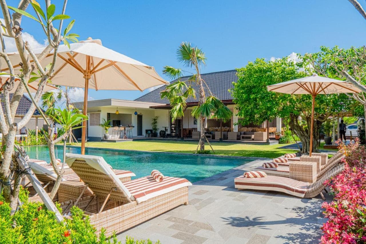 a swimming pool with lounge chairs and umbrellas at Green D'mel Bali in Nusa Dua