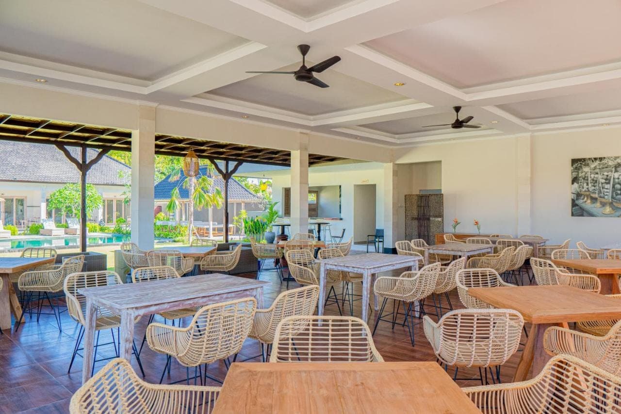 a restaurant with tables and chairs and a patio at Green D'mel Bali in Nusa Dua