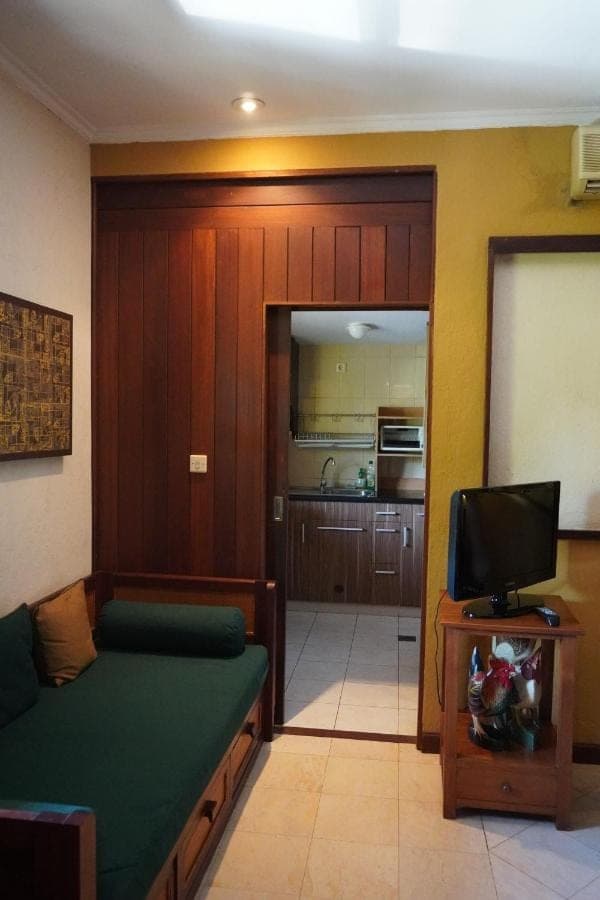a living room with a couch and a tv in a room at Pondok Agung Bed &amp; Breakfast in Nusa Dua