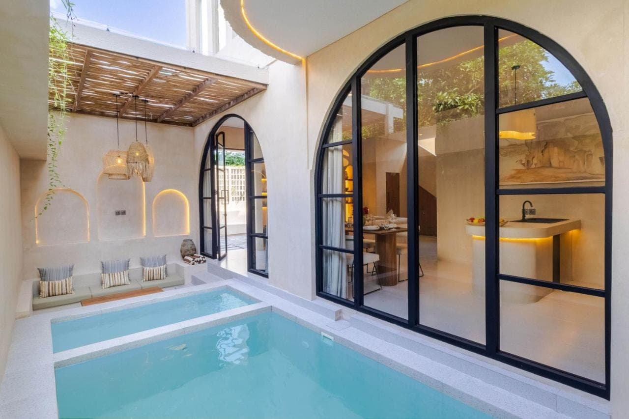 a swimming pool in a house with glass windows at Villa San Miguel by Pertama Stay in Seminyak