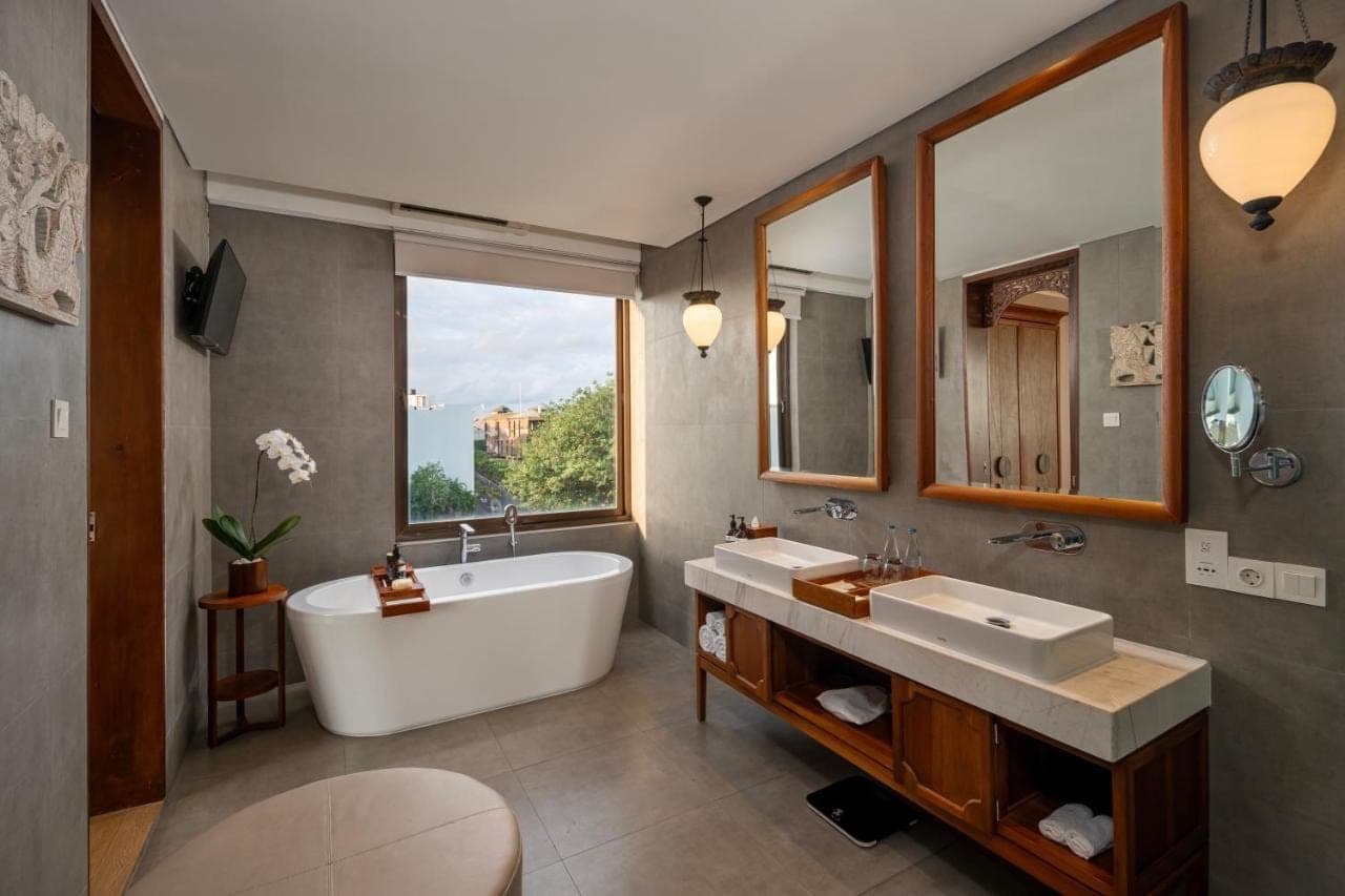a bathroom with two sinks and a tub and a large window at Kuta Seaview Beach Resort in Kuta