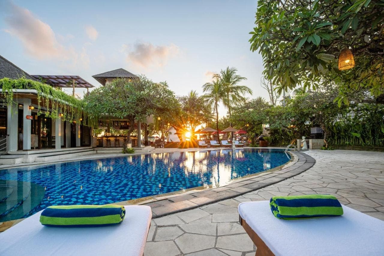 a pool at a resort with two seats in front at Kuta Seaview Beach Resort in Kuta