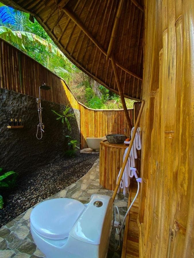 a bathroom with a toilet and a bath tub at Hidden Bamboo Village in Sidemen