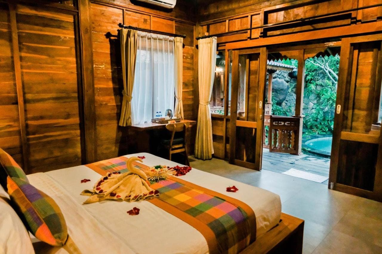 a bedroom with a bed in a room with wooden walls at Pondok Kayu Batu in Ubud
