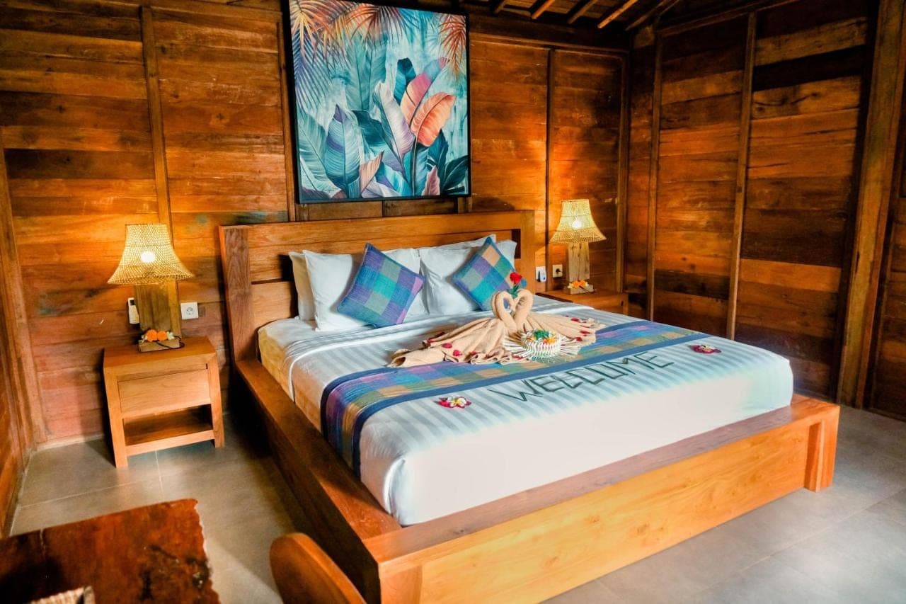 a bedroom with a bed in a room with wooden walls at Pondok Kayu Batu in Ubud