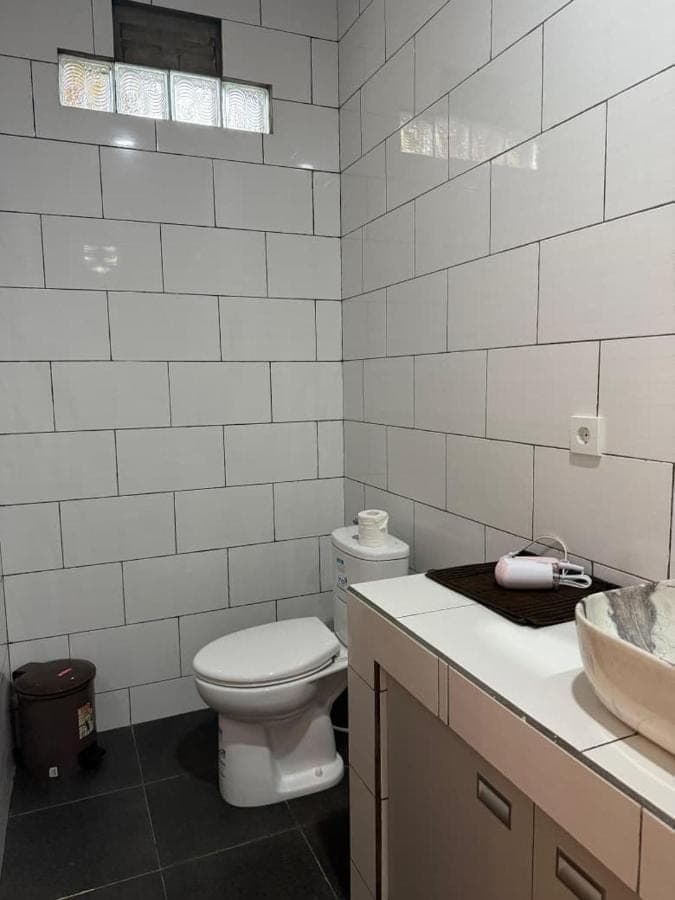 a white bathroom with a toilet and a sink at Willy Homestay in Uluwatu
