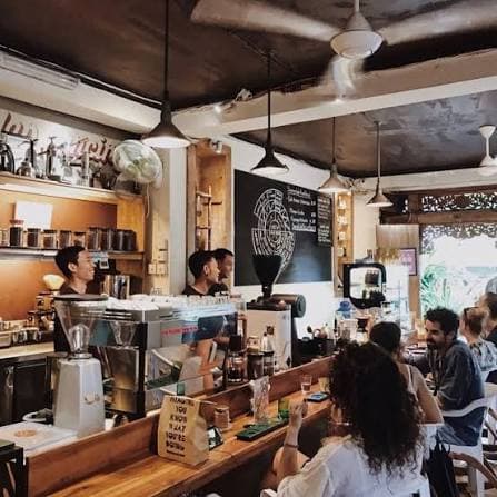 Baristas behind the espresso machine and people sitting at the bar