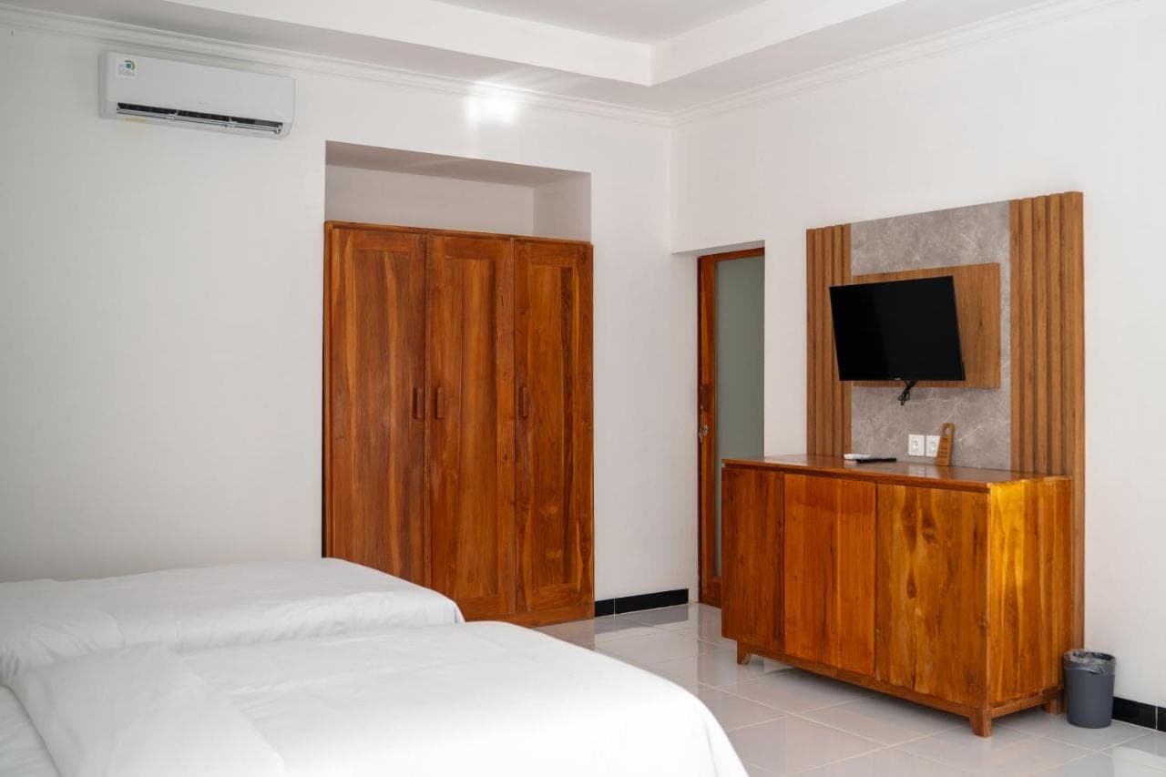 a bedroom with two beds and a tv on a wooden cabinet at Kasturi Uluwatu in Uluwatu