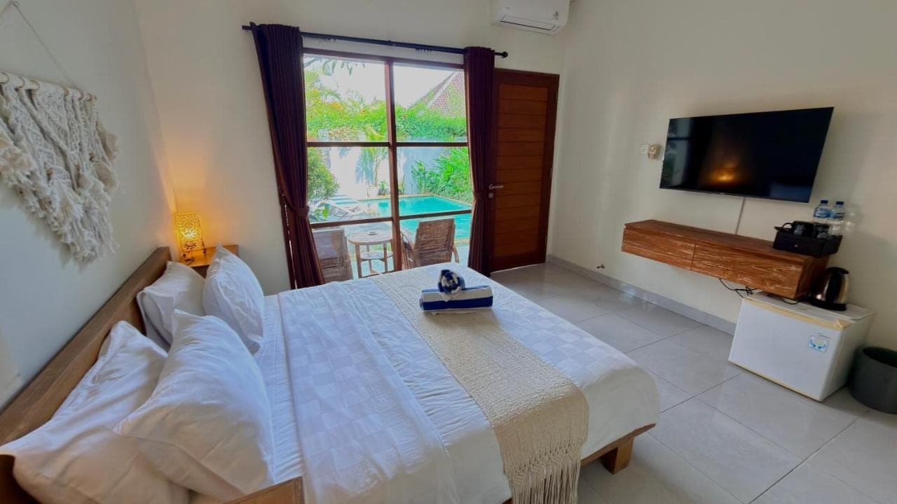 a bedroom with a bed and a tv and a window at Moonlight Sanur in Sanur
