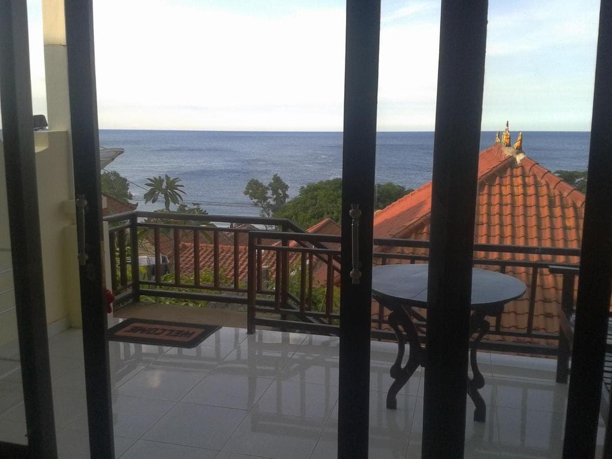 a room with a view of the ocean from a balcony at Sinar Bali 2 in Amed
