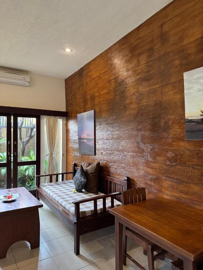 a living room with a couch and a wooden wall at Praschita Bali in Sanur