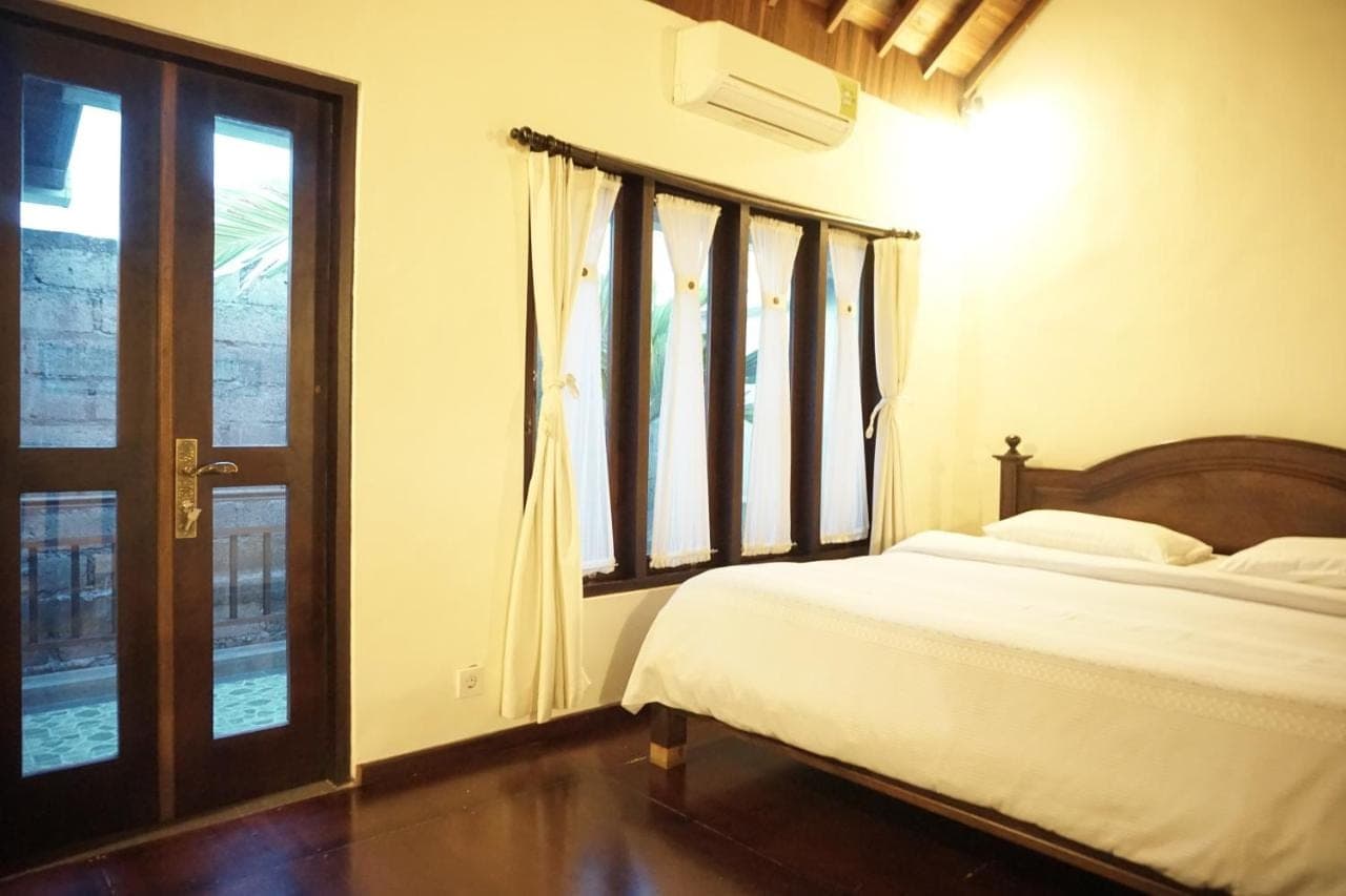 a bedroom with a bed and a window at Praschita Bali in Sanur