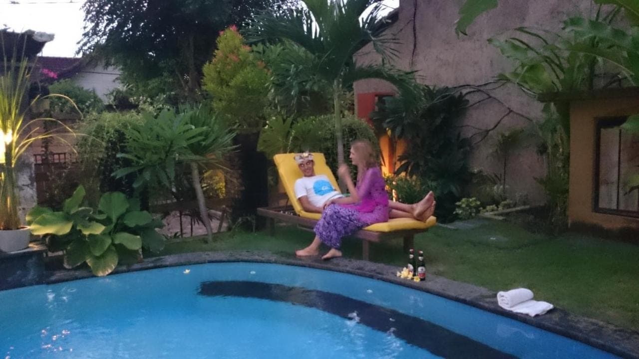 a woman sitting in a chair next to a pool at Praschita Bali in Sanur