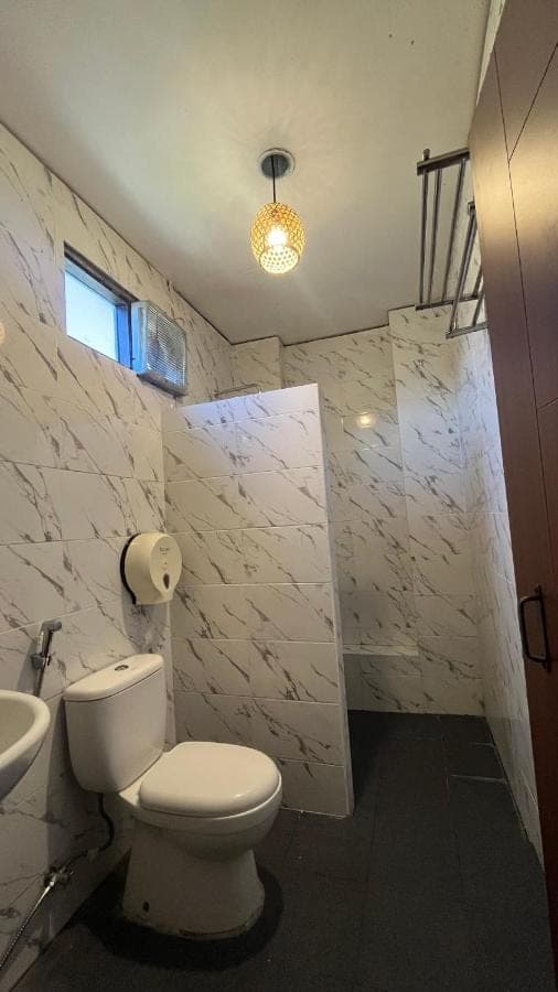 a white bathroom with a toilet and a sink at City Garden Bali Dwipa Hotel, Kuta in Kuta