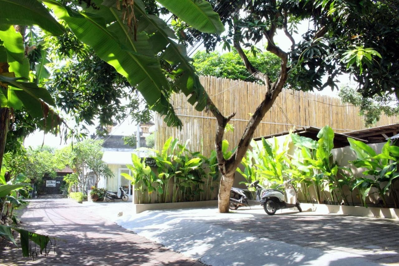 a courtyard with a tree and a fence at Rusty Seminyak in Seminyak