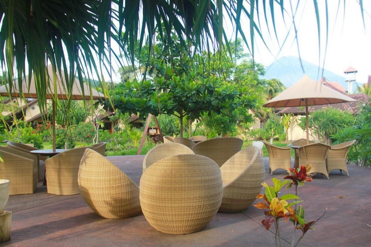 a group of chairs and tables and an umbrella at Hotel Uyah Amed Spa Resort in Amed