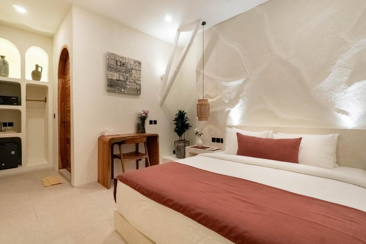 a bedroom with a large bed with a red blanket at AMARA Ocean Living -Uluwatu Padang Padang in Uluwatu