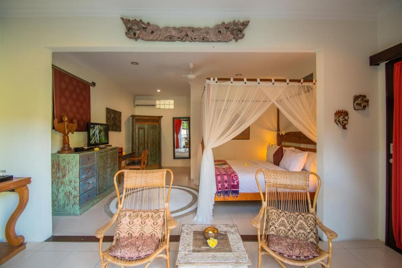 a bedroom with a bed and two chairs at Kembali Lagi Guest House in Sanur