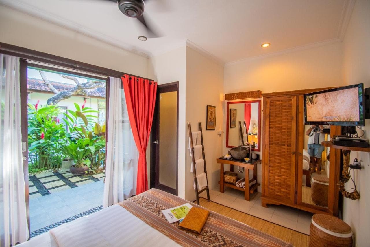 a bedroom with a bed and a sliding glass door at Kembali Lagi Guest House in Sanur