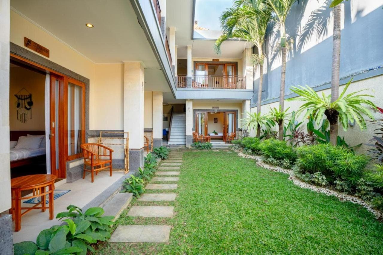 a courtyard of a building with a grass yard at Sakura Guest House in Canggu