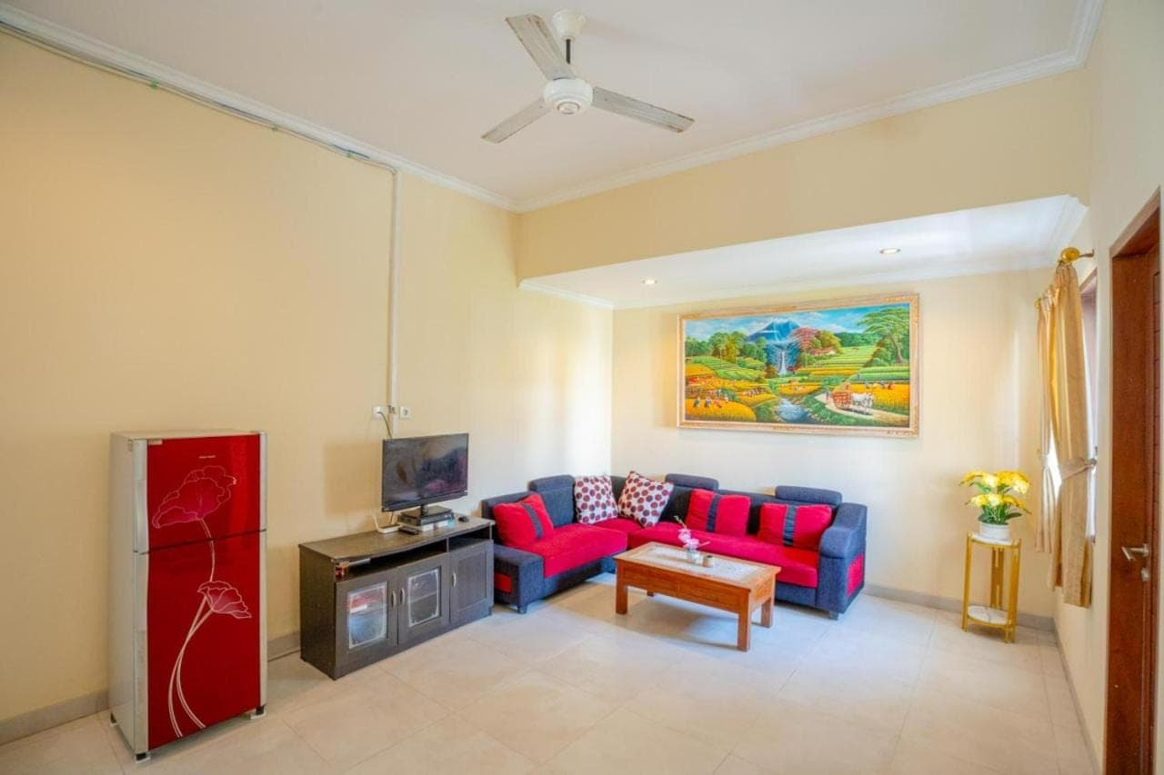 a living room with a blue couch and red chairs at Sakura Guest House in Canggu