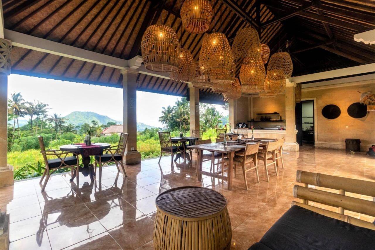 a dining room with tables and chairs and chandeliers at Pelangi Villas Sidemen by AGATA in Sidemen