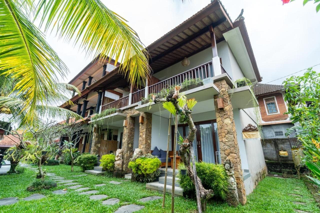 a house with a palm tree in front of it at Surawan Bisma Ubud in Ubud