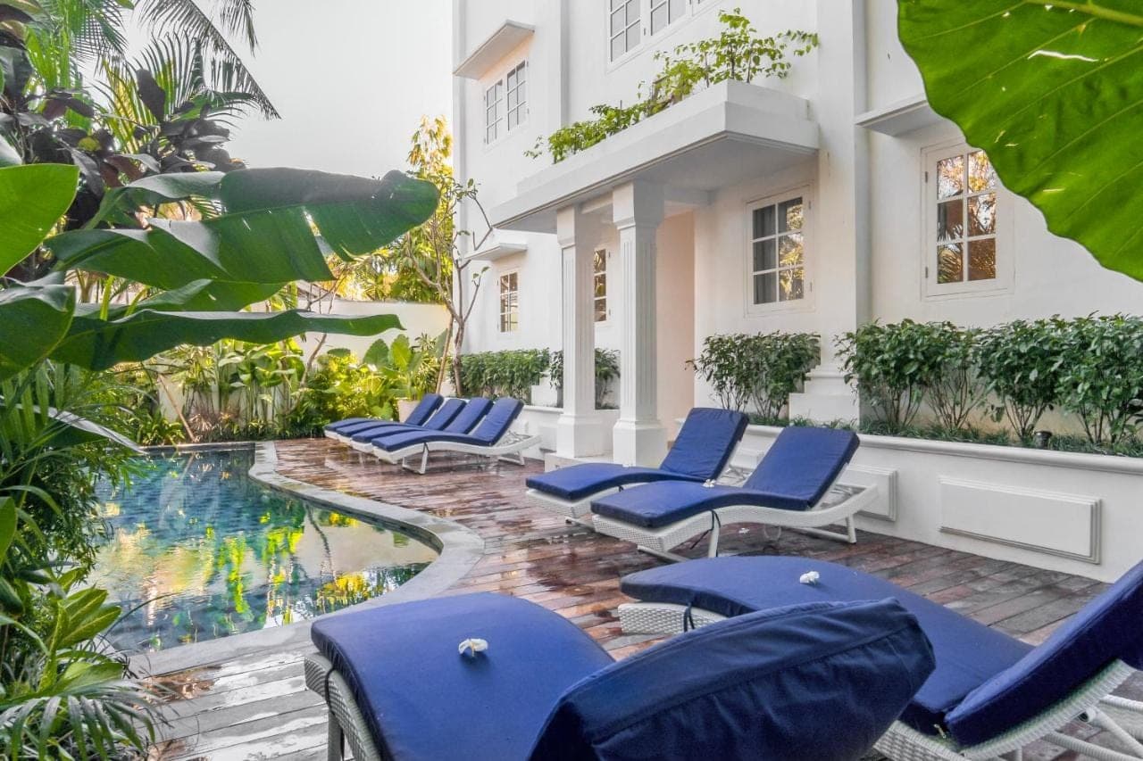 a courtyard with lounge chairs and a swimming pool at Umalas Suites in Seminyak