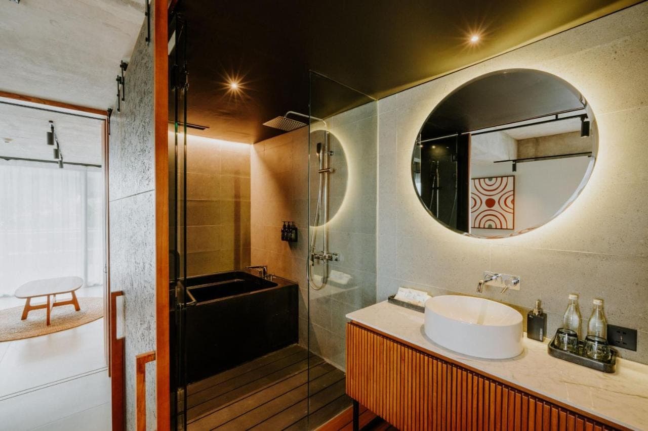 a bathroom with a sink and a tub and a mirror at The Komu Canggu Bali in Canggu