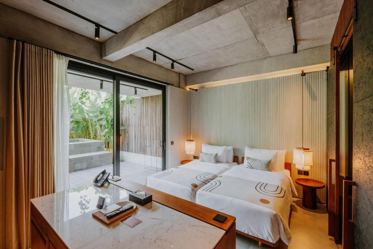 a bedroom with a large bed and a desk and a window at The Komu Canggu Bali in Canggu