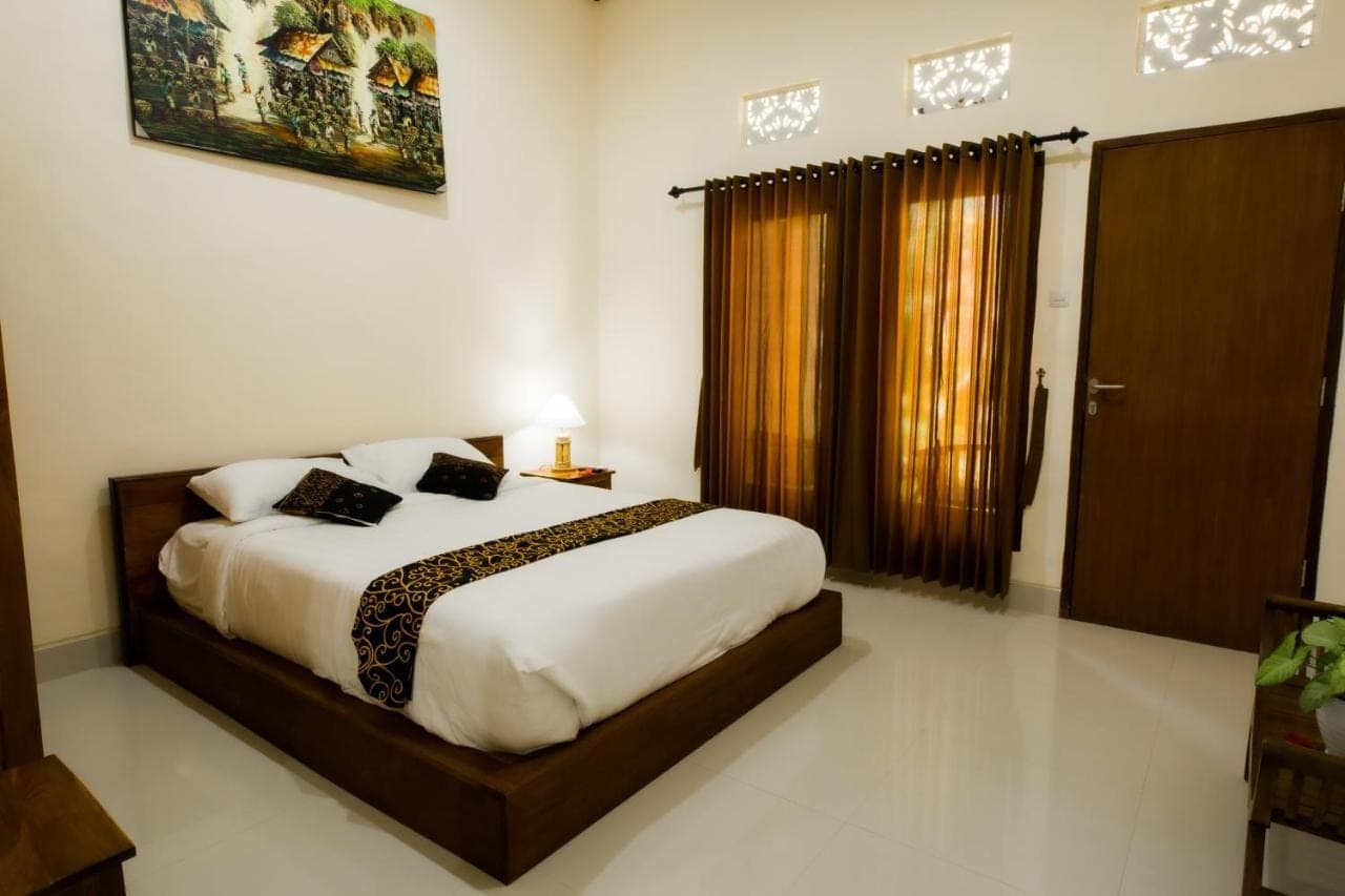 a bedroom with a bed and a large window at Manda Homestay in Sanur