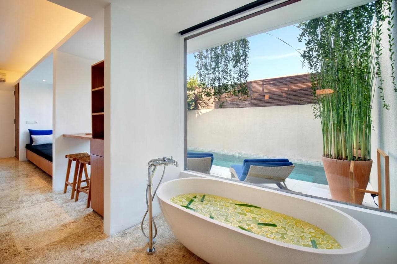 a bath tub in a room with a large window at Uma Sapna Seminyak in Seminyak
