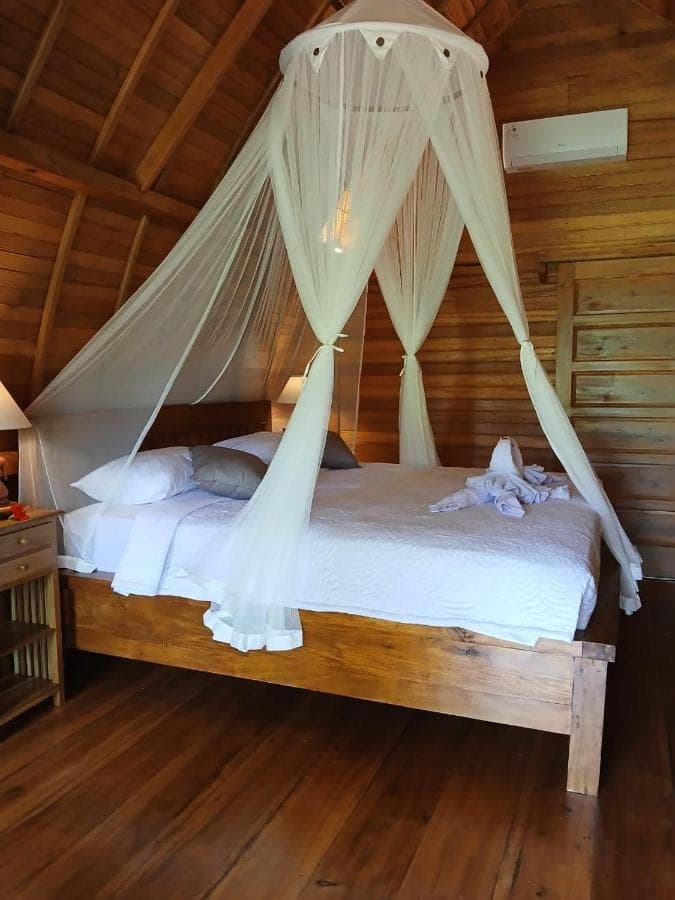 a bedroom with a bed with mosquito netting at Lumbung Umaluah Villa in Sidemen