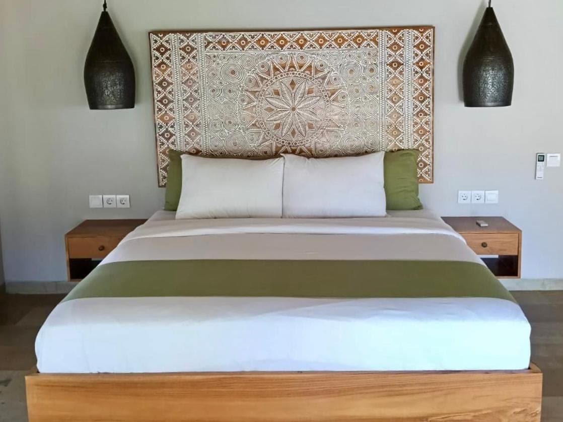 a bedroom with a large bed with two tables at Emocean Beach Boutique Dive Resort in Amed