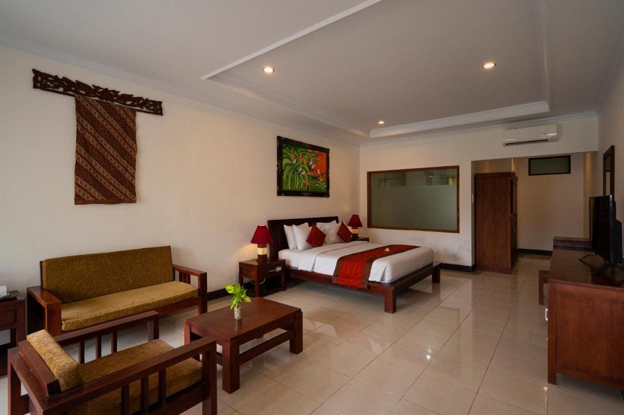 a bedroom with a bed and a couch and a tv at Kusuma Resort Seminyak in Seminyak